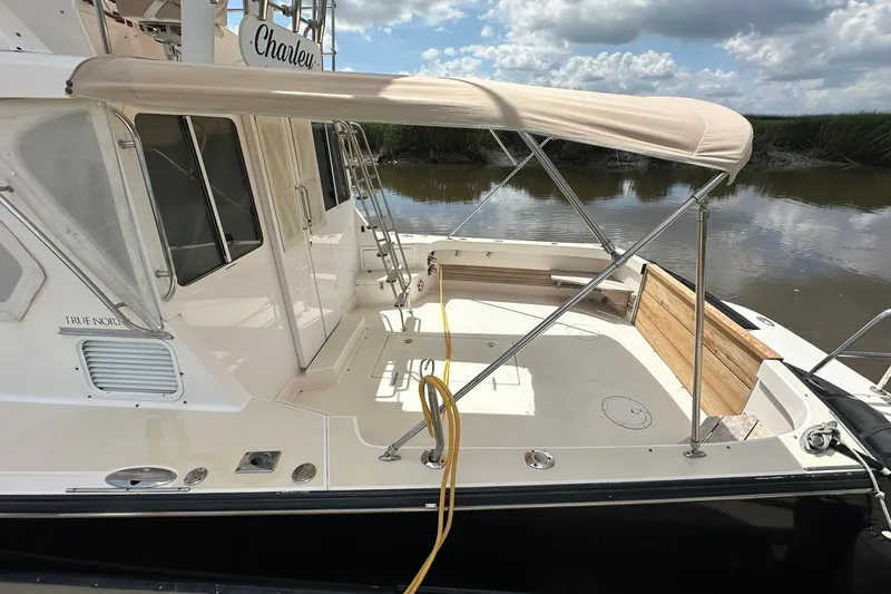Slide: The Image of 2007 True North 38 Heritage boat with canopy, docked by a calm river. - 12