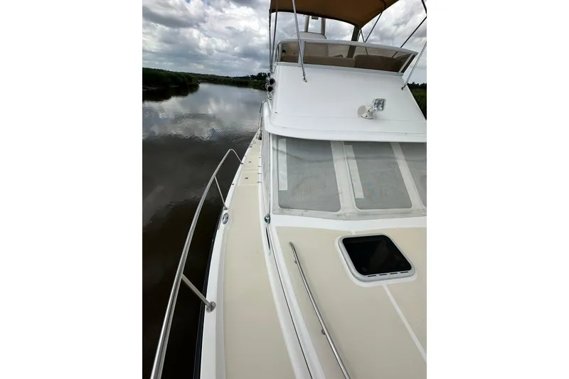Slide: The Image of 2007 True North 38 Heritage boat on calm river under cloudy sky. - 32