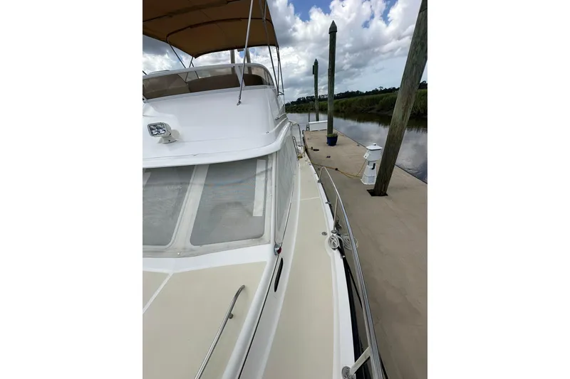 Slide: The Image of 2007 True North 38 Heritage yacht docked by a calm river under a cloudy sky. - 33