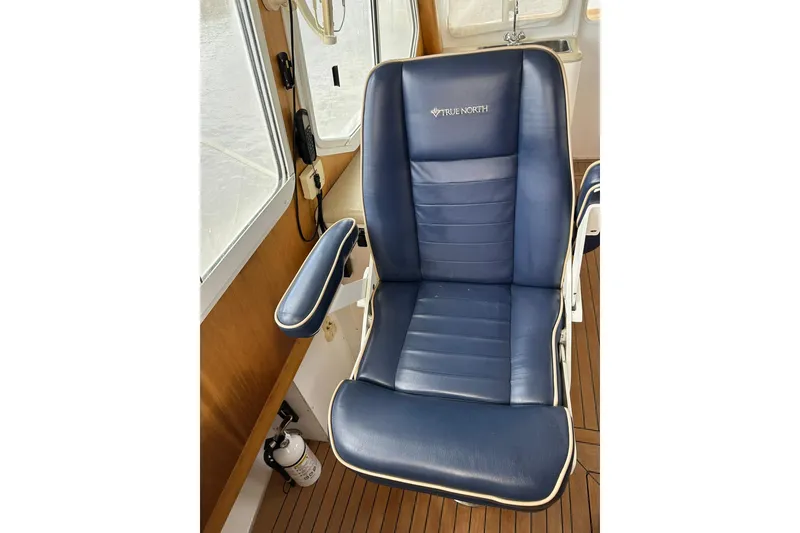 Slide: The Image of Blue captain's chair on 2007 True North 38 Heritage boat, featuring wood interior and window view. - 112