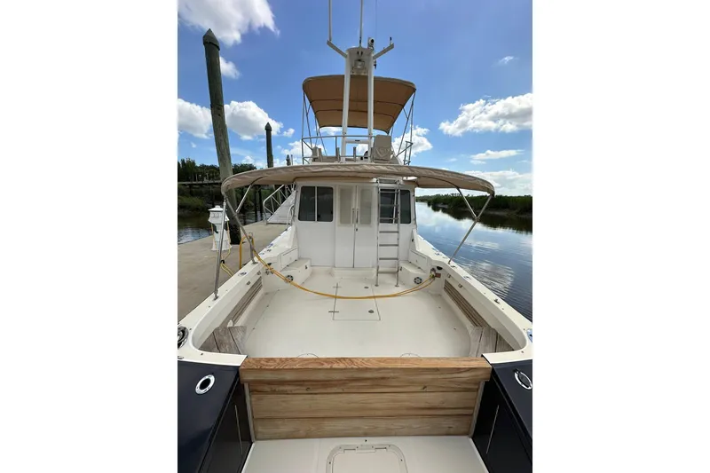 Slide: The Image of 2007 True North 38 Heritage boat docked, featuring spacious deck and flybridge under clear sky. - 16