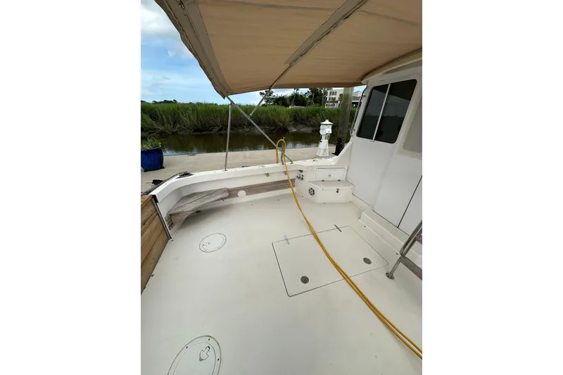 Slide: The Image of 2007 True North 38 Heritage boat deck with canopy, docked by lush greenery. - 22