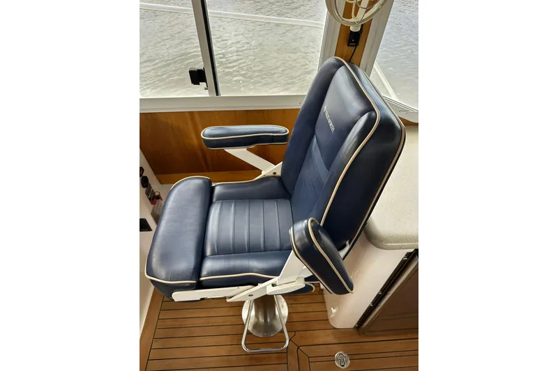 Slide: The Image of Captain's chair on 2007 True North 38 Heritage boat, featuring blue upholstery and wooden flooring. - 111