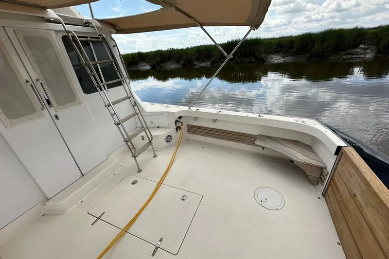 Slide: The Image of Deck view of 2007 True North 38 Heritage boat with canopy and ladder by the water. - 24