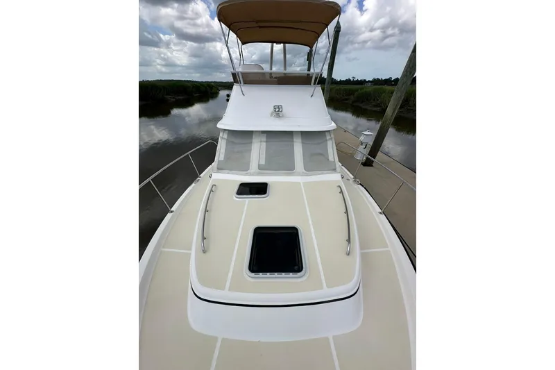 Slide: The Image of 2007 True North 38 Heritage yacht with beige deck and canopy, docked by a serene river. - 31