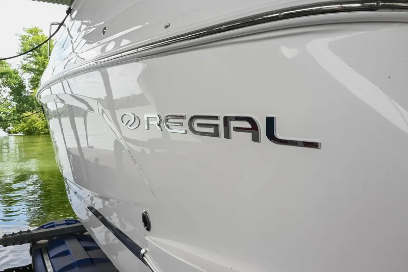 Slide: The Image of 2025 Regal 28 Express boat, sleek white exterior, docked by the water. - 5