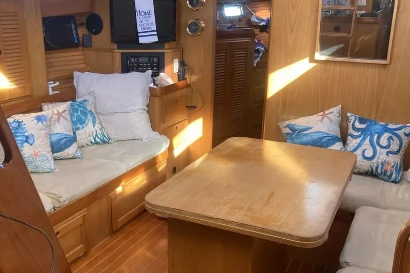 Slide: The Image of Cozy 1995 Freedom 45 CC yacht interior with nautical-themed cushions and wooden furnishings. - 10