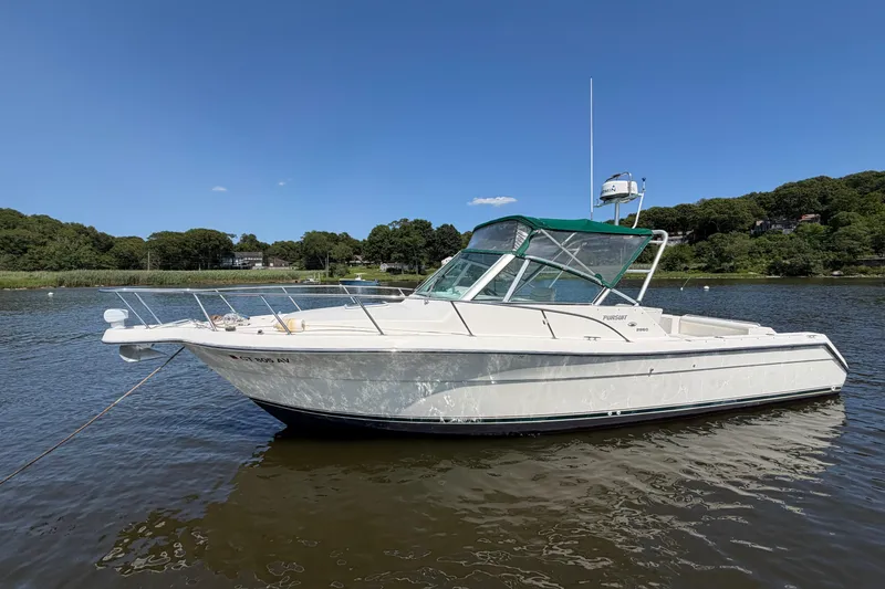 The Image of 1998 Pursuit 2860 Denali boat anchored on a calm lake under a clear blue sky. - 0