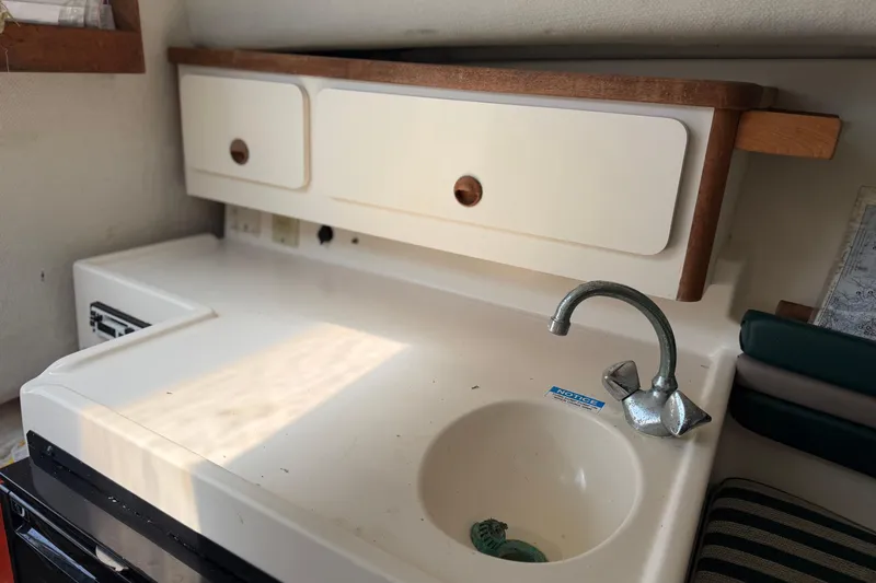 Slide: The Image of Compact kitchen area in a 1998 Pursuit 2860 Denali boat with sink and storage. - 2