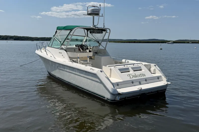 Slide: The Image of 1998 Pursuit 2860 Denali boat named Dolcetto on calm water, featuring a green canopy. - 12