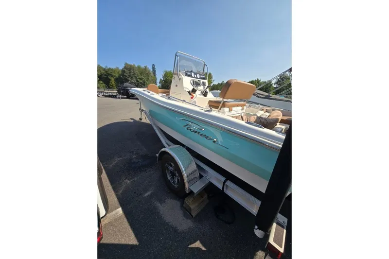 Slide: The Image of 2023 Pioneer 180 Islander boat on trailer, parked outdoors under clear blue sky. - 4