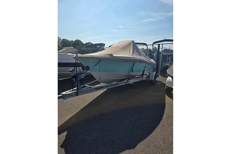 Slide: The Image of 2023 Pioneer 180 Islander boat covered on a trailer in a sunny outdoor setting. - 1