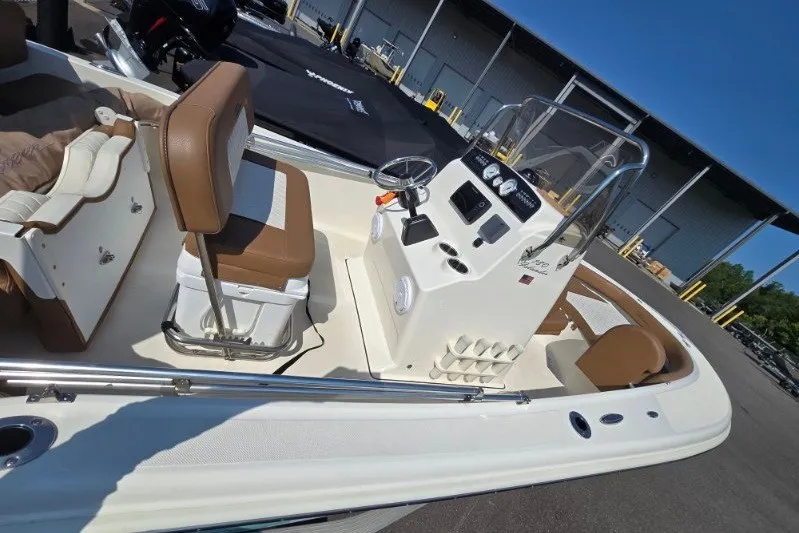 Slide: The Image of 2023 Pioneer 180 Islander boat interior with console and seating, docked outdoors. - 6