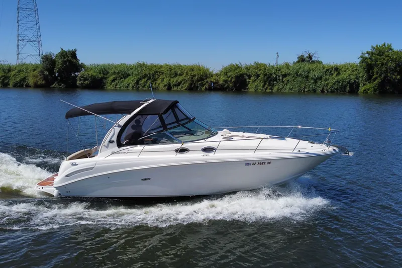 Slide: The Image of 2005 Sea Ray 300 Sundancer cruising on a calm river under clear blue skies. - 2