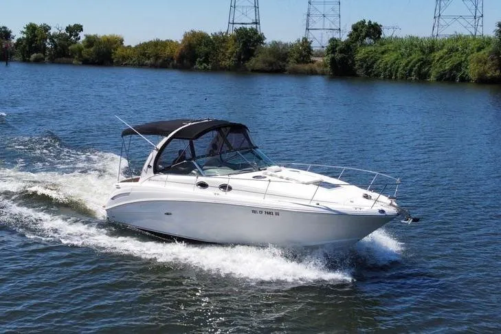 The Image of 2005 Sea Ray 300 Sundancer cruising on a calm river with lush greenery. - 1