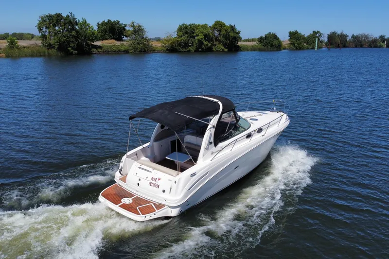 Slide: The Image of 2005 Sea Ray 300 Sundancer cruising on a serene lake under clear blue skies. - 3