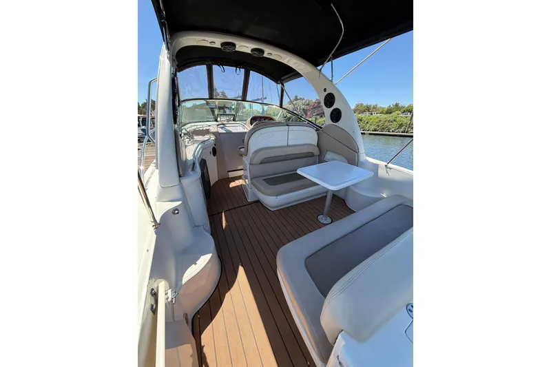 Slide: The Image of 2005 Sea Ray 300 Sundancer boat interior with seating and table, docked by water. - 5