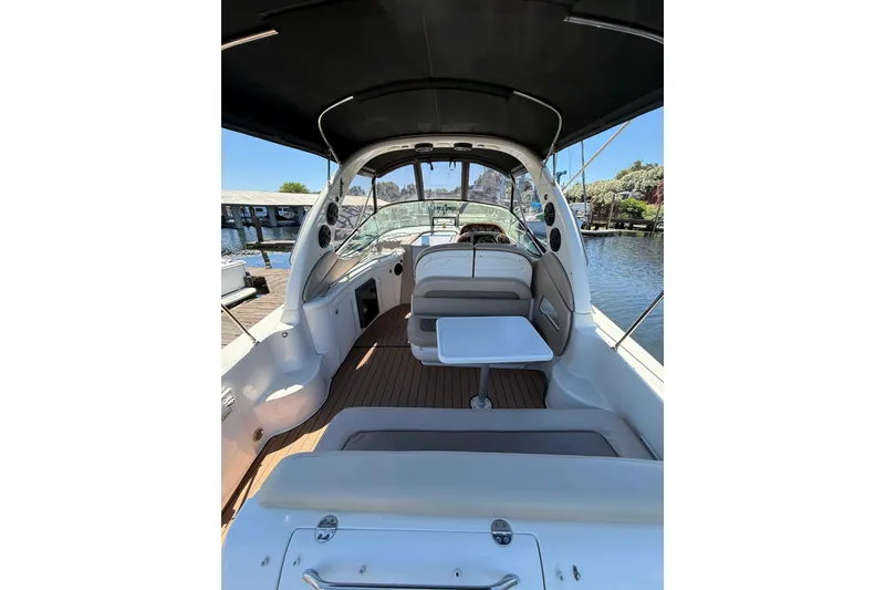 Slide: The Image of 2005 Sea Ray 300 Sundancer boat interior with seating and table, docked by the water. - 6