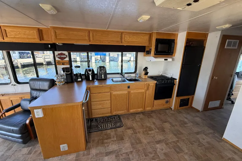 Slide: The Image of Interior of a 1998 Patio Cruiser 55 houseboat kitchen with wooden cabinets and appliances. - 17