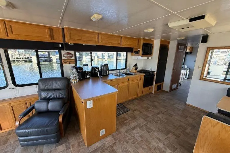 Slide: The Image of Interior of a 1998 Patio Cruiser 55 houseboat with kitchen and seating area. - 14