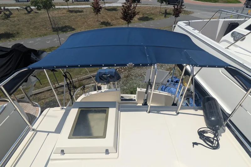 Slide: The Image of 2001 Nordic Tug 32 with blue canopy, docked in a marina. - 11