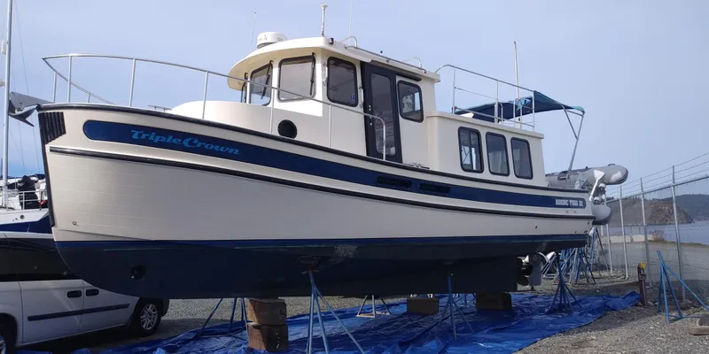 The Image of 2001 Nordic Tug 32 on stands in a boatyard, with a blue tarp underneath. - 0