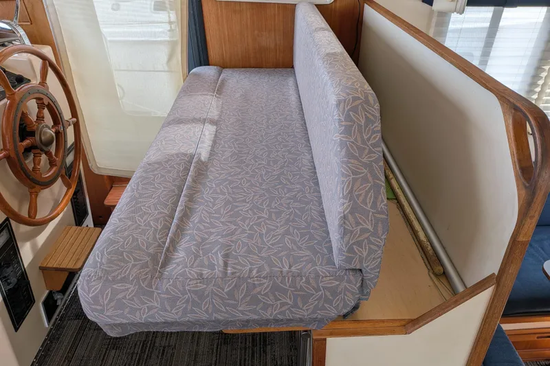 Slide: The Image of Interior of a 2001 Nordic Tug 32 featuring a cushioned bench and wooden steering wheel. - 46