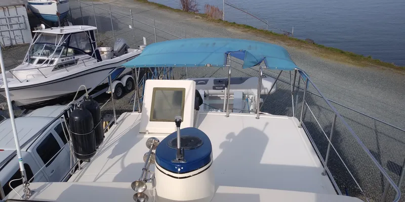 Slide: The Image of A 2001 Nordic Tug 32 is on land next to another boat. It features a blue sunshade. - 11