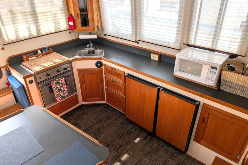 Slide: The Image of Cozy kitchen in a 2001 Nordic Tug 32 boat with wooden cabinetry and modern appliances. - 27