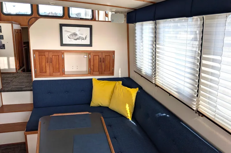 Slide: The Image of Interior of 2001 Nordic Tug 32 with blue seating, yellow pillows, and wooden cabinetry. - 22
