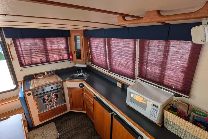 Slide: The Image of Interior of a 2001 Nordic Tug 32, featuring a compact kitchen with wooden cabinetry. - 29