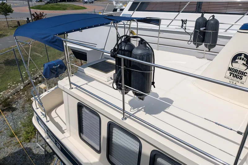 Slide: The Image of 2001 Nordic Tug 32 boat with blue canopy and deck equipment, docked in a marina. - 10