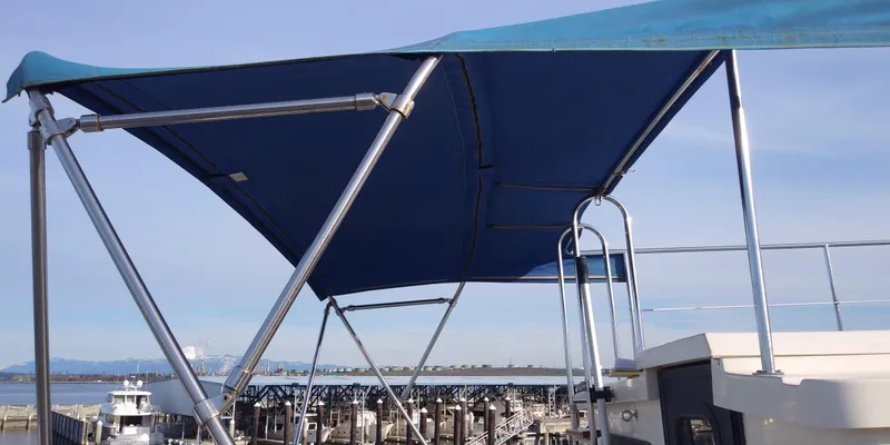 Slide: The Image of A 2001 Nordic Tug 32 with a blue sunshade at the harbor. - 6