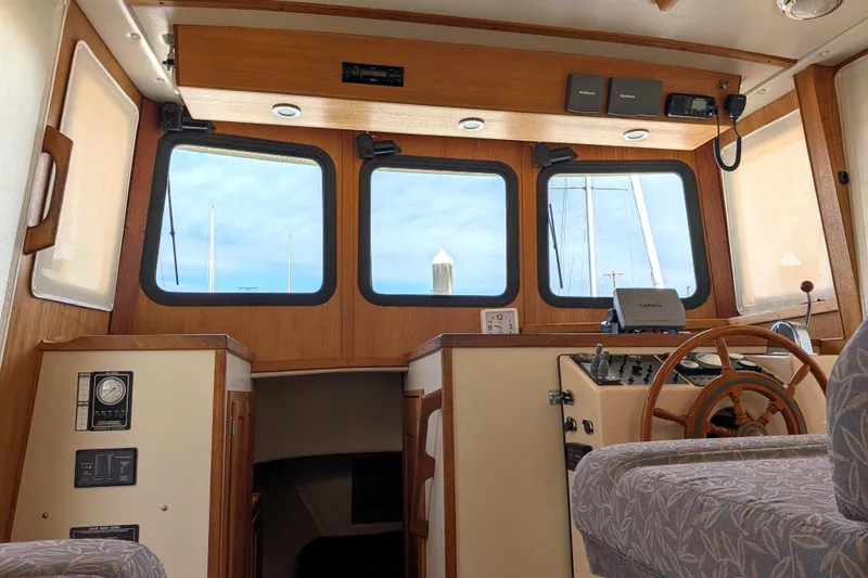 Slide: The Image of Interior view of a 2001 Nordic Tug 32 boat, featuring a wooden helm and navigation equipment. - 31