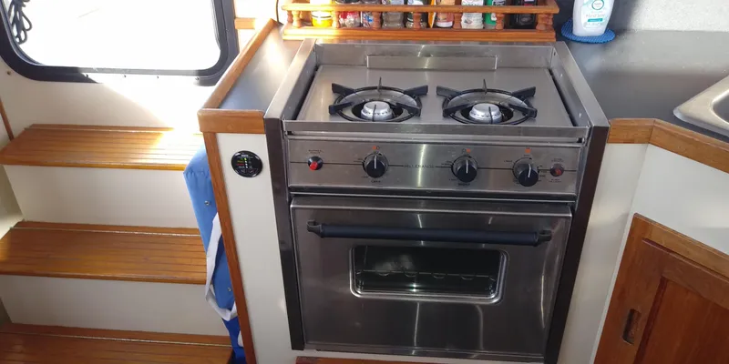 Slide: The Image of A stainless steel stove with two burners and an oven, surrounded by wood paneling and shelves. - 22