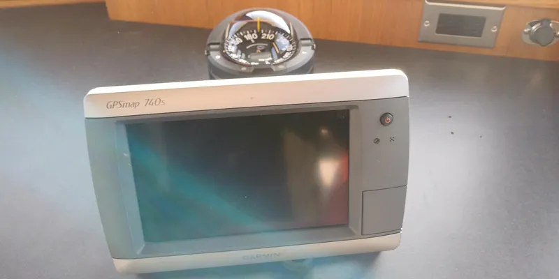 Slide: The Image of A GPS device on a boat table, with a compass in the background. - 29