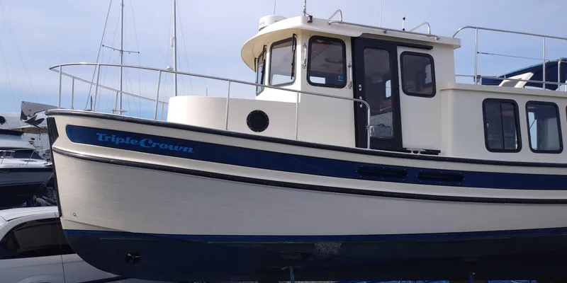 Slide: The Image of A 2001 Nordic Tug 32 with a blue stripe and cabin. - 1
