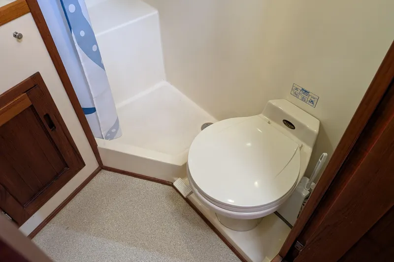 Slide: The Image of Bathroom interior of a 2001 Nordic Tug 32, featuring a compact toilet and shower area. - 55
