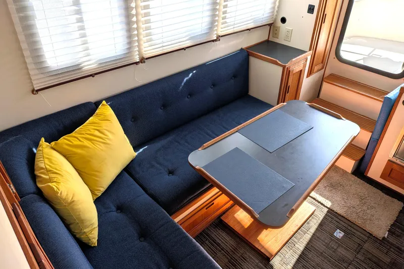 Slide: The Image of Cozy interior of a 2001 Nordic Tug 32 with blue seating and yellow pillows. - 26