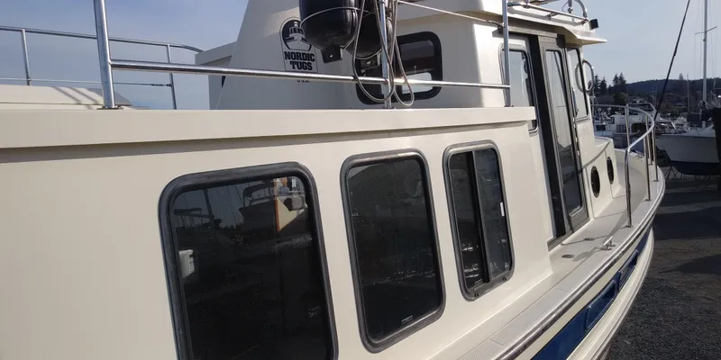 Slide: The Image of A 2001 Nordic Tug 32 with a cream exterior and large windows. - 16