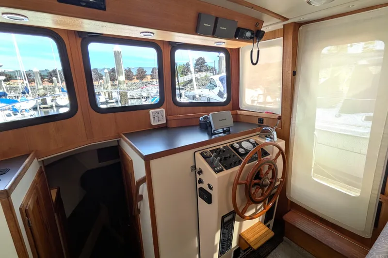 Slide: The Image of Interior helm of a 2001 Nordic Tug 32 with wooden steering wheel and navigation equipment. - 32