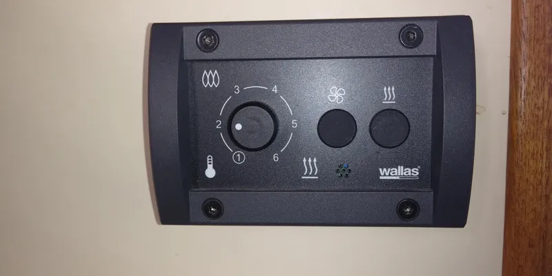 Slide: The Image of A wall thermostat with a dial and buttons, mounted on a wooden panel. - 26