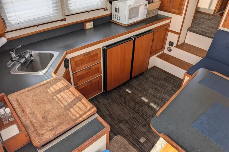 Slide: The Image of 2001 Nordic Tug 32 interior kitchen with wooden cabinetry, sink, and microwave. - 24