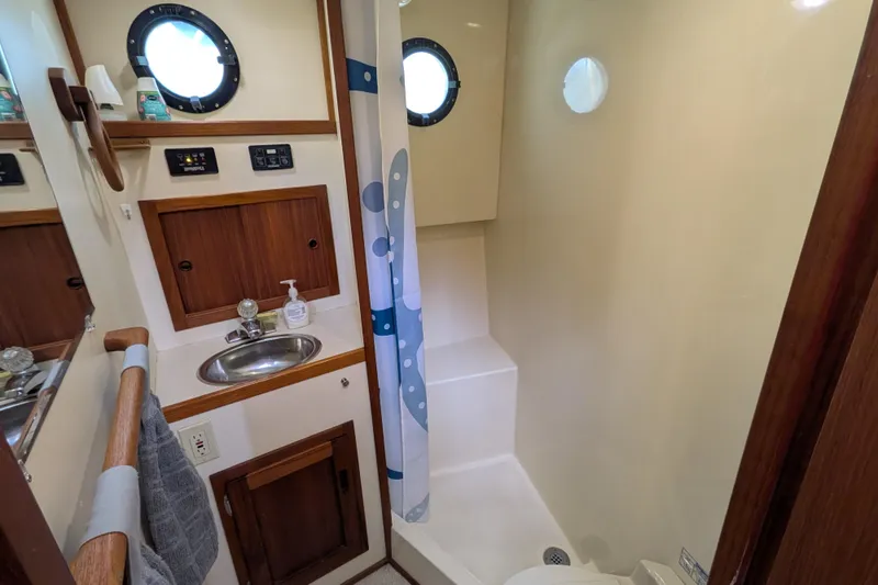 Slide: The Image of 2001 Nordic Tug 32 bathroom with sink, shower, and porthole windows. - 53