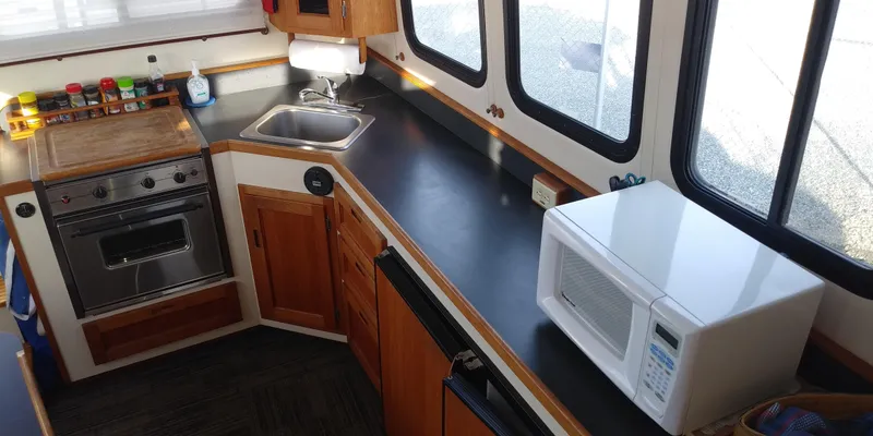 Slide: The Image of The galley of a 2001 Nordic Tug 32 with a stove, sink, and microwave. - 20