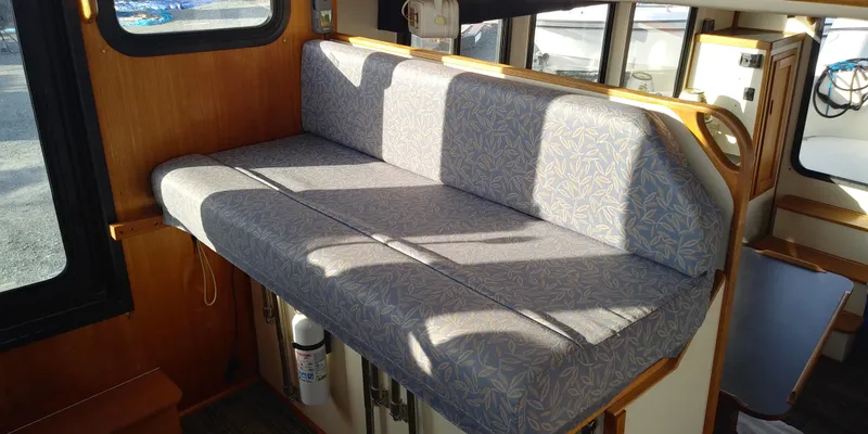 Slide: The Image of Interior of a 2001 Nordic Tug 32 with cushioned seating and wooden accents. - 32