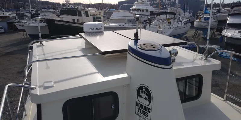 Slide: The Image of A 2001 Nordic Tug 32 in a marina, featuring a solar panel and Garmin equipment. - 9