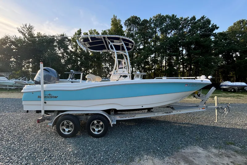 Slide: The Image of 2018 NauticStar 211 Coastal boat on trailer, parked outdoors near trees. - 4