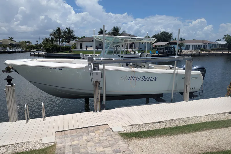 The Image of 2023 Sailfish 290 CC boat docked by waterfront homes under a clear sky. - 1