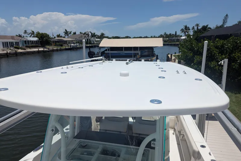 Slide: The Image of 2023 Sailfish 290 CC boat docked by a scenic waterfront with clear skies. - 13
